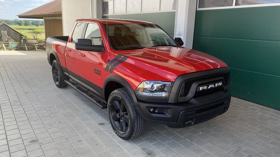 RAM 1500 Warlock in Flame Red, schräg von vorn vor einer bayerischen Scheune geparkt