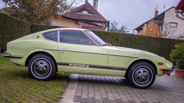 Lime Yellow 1972 Datsun 240Z in Switzerland, full side profile showing the long bonnet, 240Z stripe and chrome bumpers