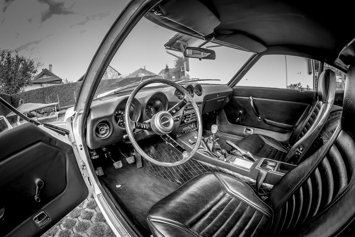 Wide interior view of a Datsun 240Z showing the dashboard, steering wheel and seats