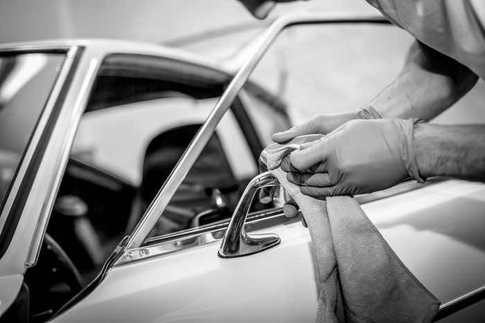 Machine polisher working across the bodywork of a Datsun 240Z