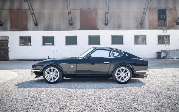 Side profile of a dark metallic black 1975 Datsun 280Z widebody showing the full S30 shape and flared arches