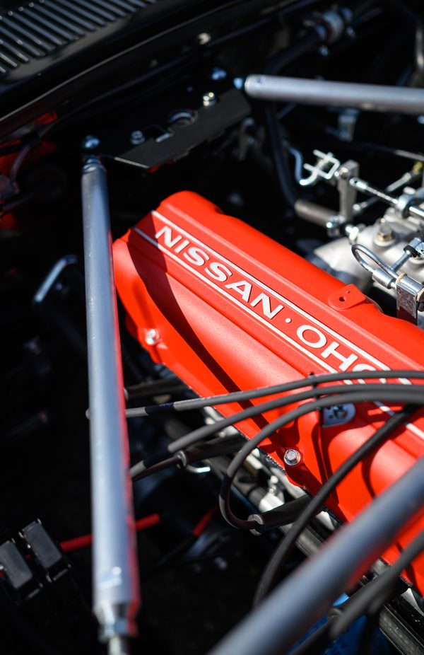 Red Nissan OHC cam cover and polished engine bay bracing on the L28 six of a 1975 Datsun 280Z