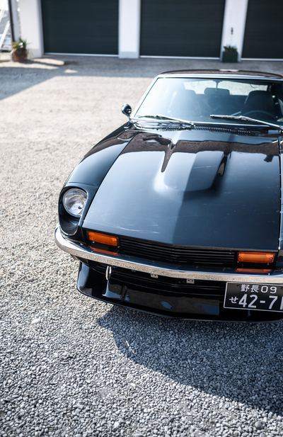 Bonnet and headlight of a black Datsun 280Z seen from the front