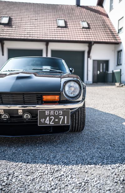 Headlight and front corner of a black Datsun 280Z