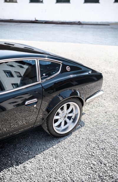 Flared rear arch and wheel of a black Datsun 280Z widebody