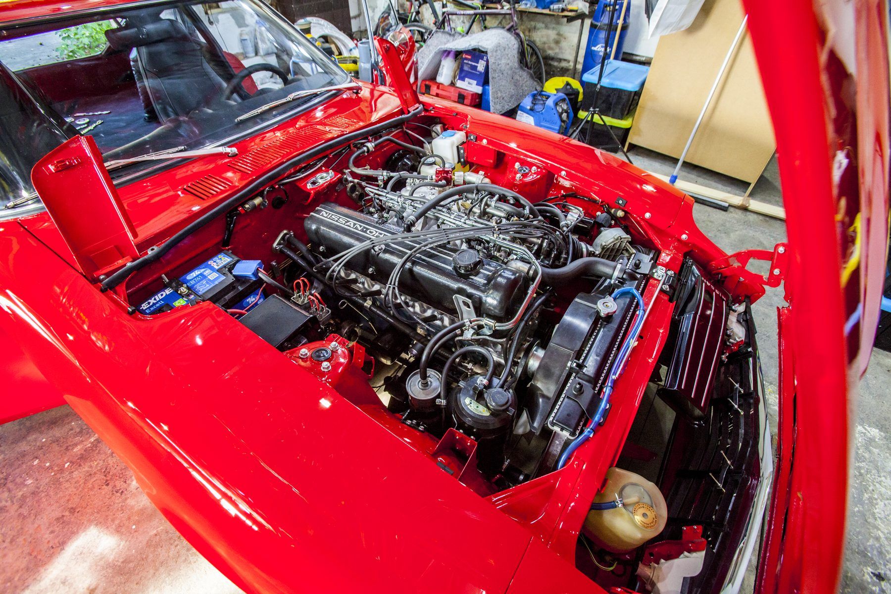Engine bay of a 1976 Datsun 280Z with the L28 inline-six on individual throttle bodies, replacing the L-Jetronic manifold