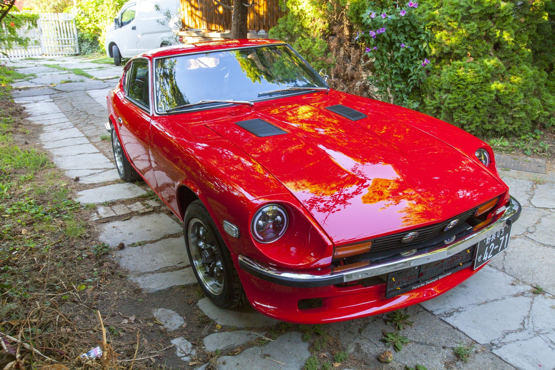 Red 1976 Datsun 280Z front three-quarter in daylight, long bonnet and low nose of the S30 shape