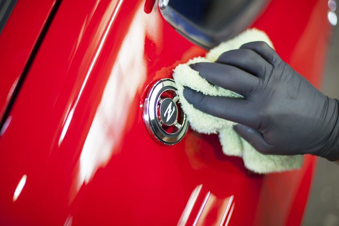 Fuel filler cap being polished during final detailing of a Datsun 280Z