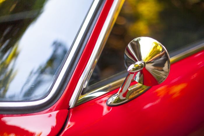 Chrome bullet mirror on a red Datsun 280Z photographed in outdoor light
