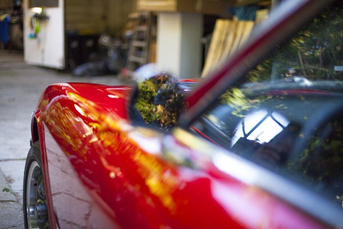 Rear wheel arch of a red Datsun 280Z with reflections in the paint