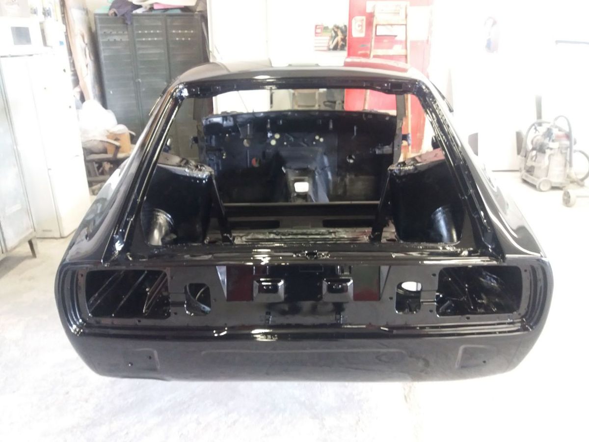 Deep gloss black paint detail on a restored Datsun 280Z shell — rear view