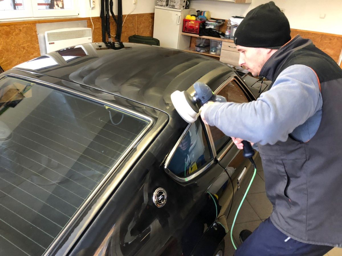 Machine polishing a restored black Datsun 280Z during the 72-hour final detailing