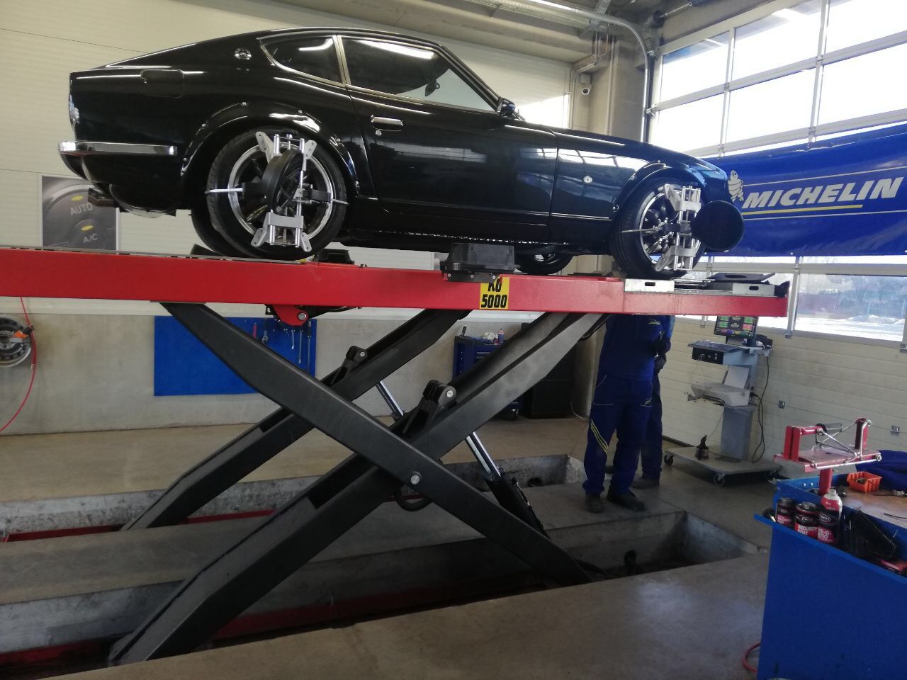 Restored black Datsun 280Z on the lift for four-wheel laser alignment during shakedown testing