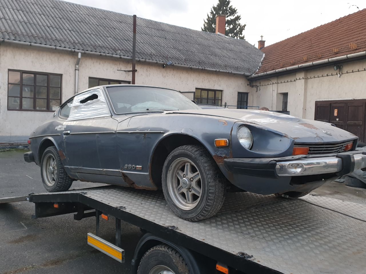 1976 Datsun 280Z on a flatbed after shipping from the USA to Europe for restoration — side profile