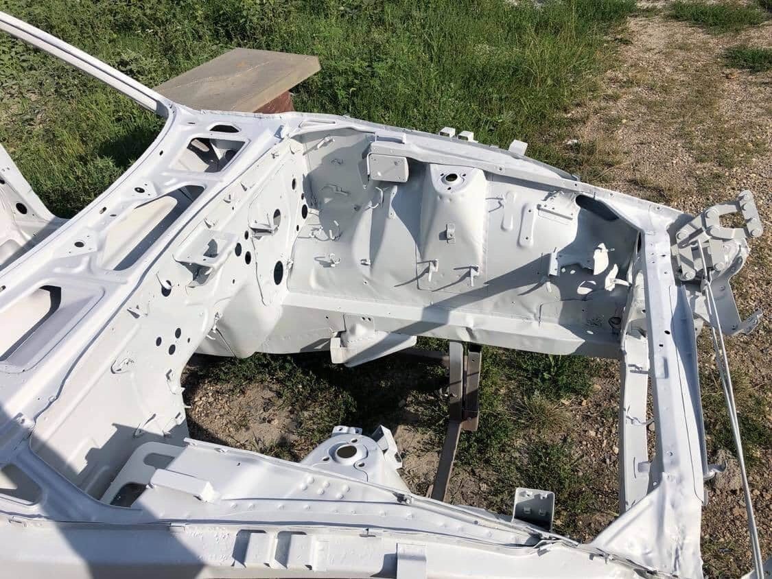 Underside of a Datsun 280Z media blasted to bare metal on a rotisserie, full extent of corrosion visible