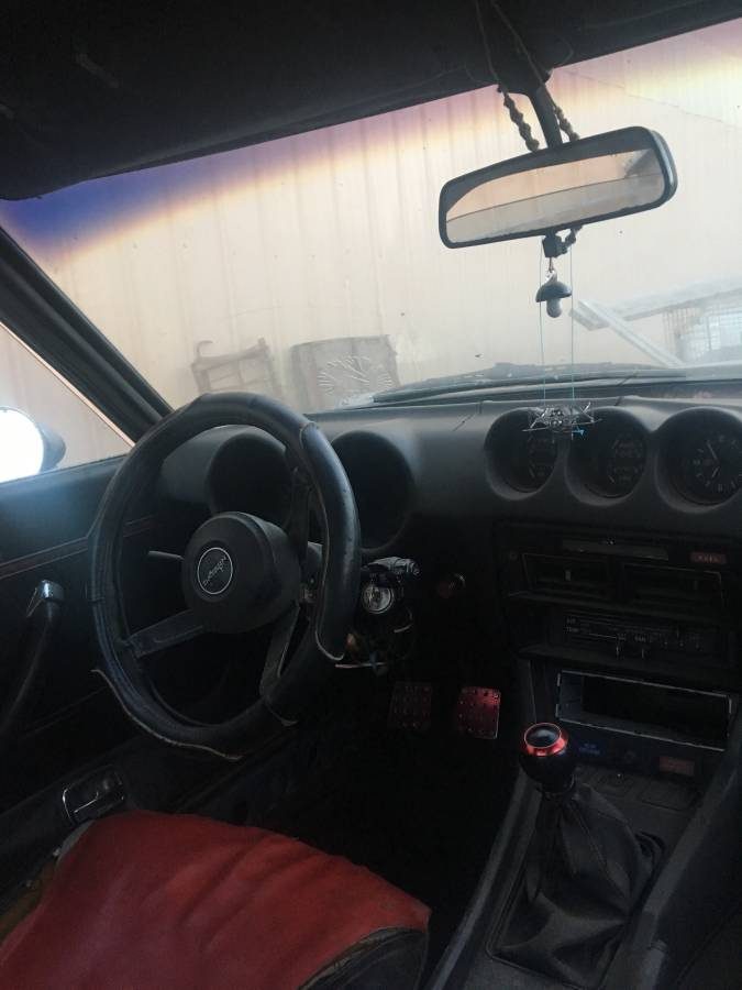 1976 Datsun 280Z barn find in Idaho — blue-grey paint, parked beside a metal barn before restoration