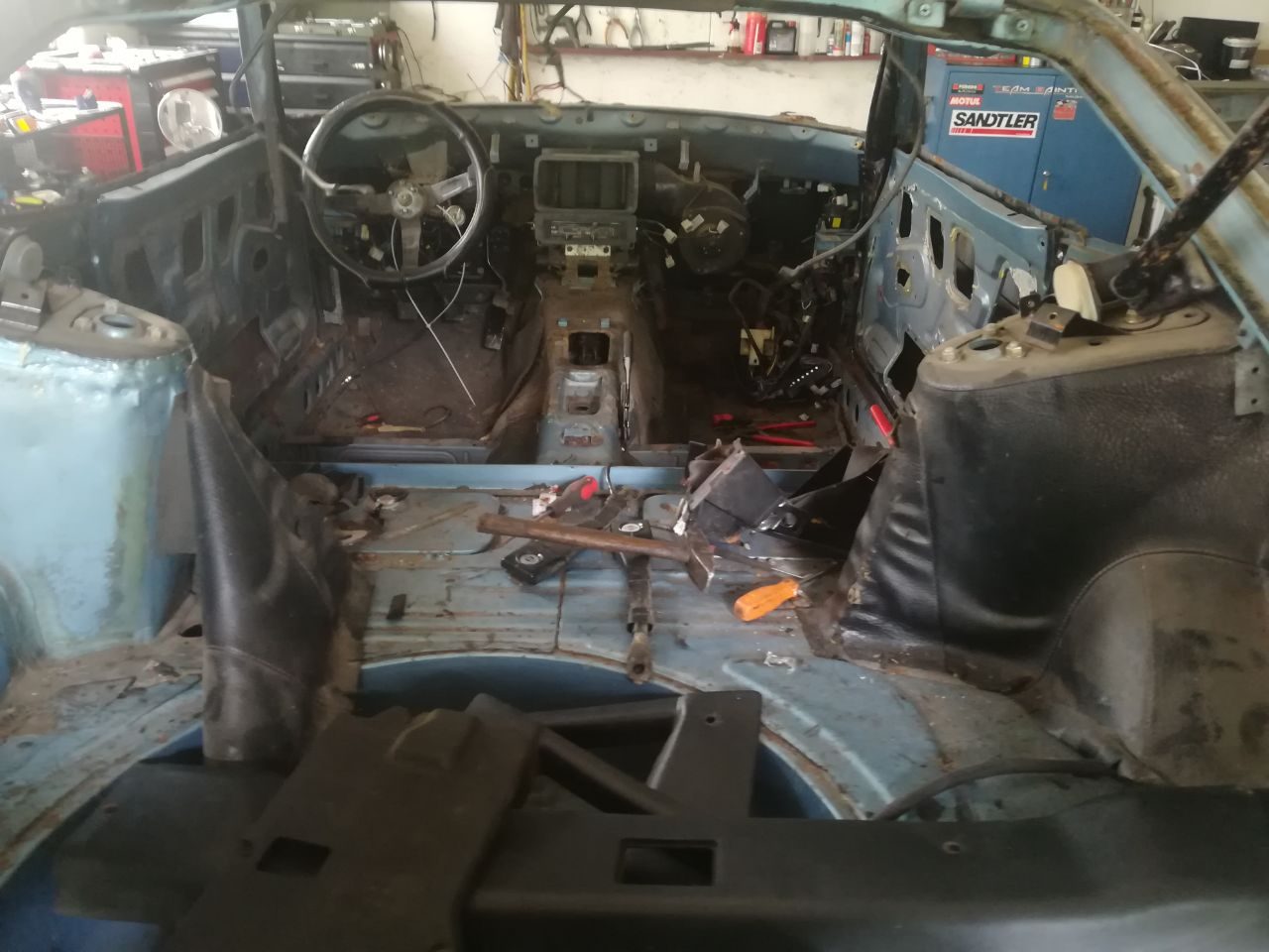 Datsun 280Z cabin stripped during teardown, dashboard removed and wiring exposed on the bare floor