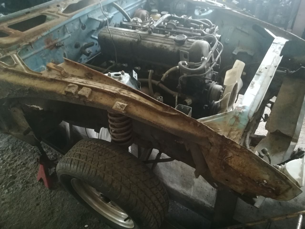 Heavy surface rust across the exposed frame rail and inner structure of the Datsun 280Z during strip-down